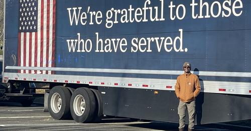we're grateful to those who have served printed on semi truck with smiling veteran standing in front